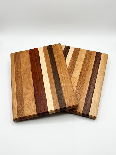 Long Grain wooden cutting boards with a selection of light and dark hardwood grain, photographed on a clean white background.