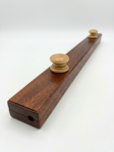 Sapele quilt hanger is a clamp-style hanger that won't damage your quilt, with round wooden knobs and visible wood grain on a white background.